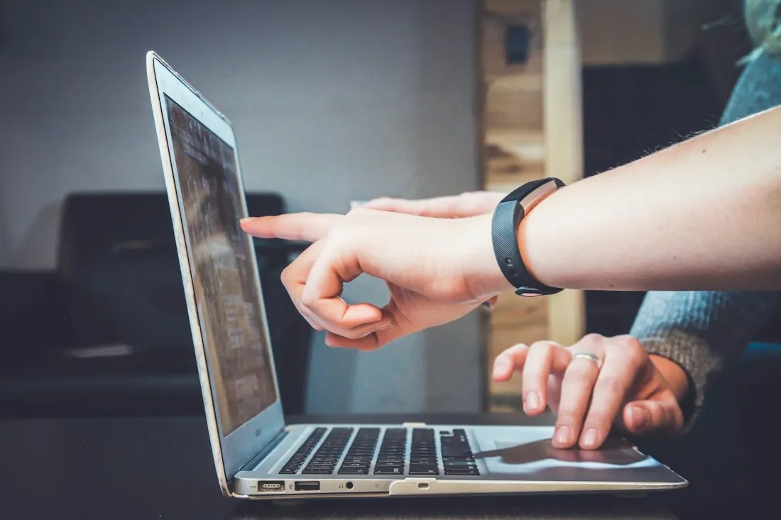 Twee mensen wijzen naar een laptopscherm